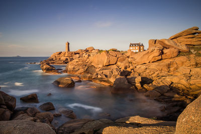 Rocks on shore by sea against sky