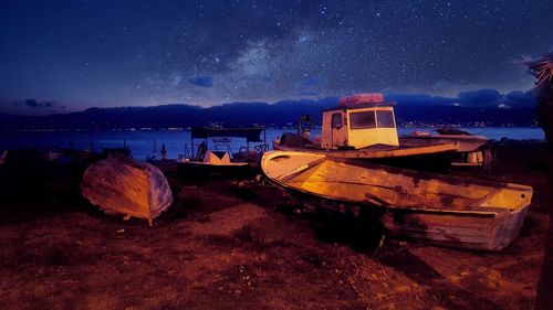 Boats moored on sea against sky at night