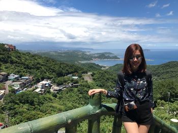 Portrait of young woman standing against landscape