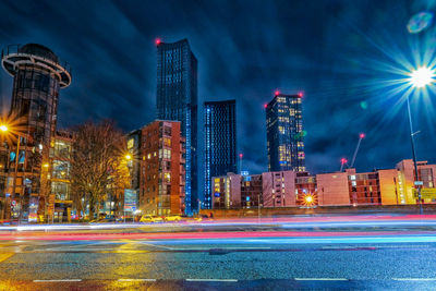 Light trails on road against buildings at night
