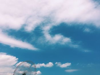 Low angle view of ferris wheel against cloudy blue sky