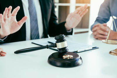 Midsection of lawyer holding gavel on table