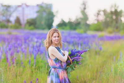 Young attractive woman holding a basket full of lupine flowers