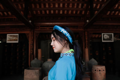 Portrait of young woman standing outside house