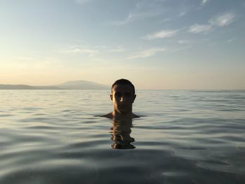 Portrait of man in sea against sky during sunset