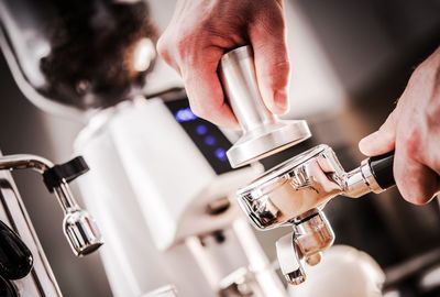 Cropped image of barista holding portafilter at coffee shop