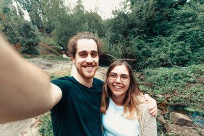 Portrait of smiling friends standing against trees