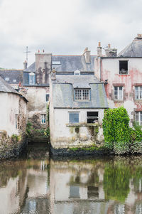 Buildings by canal against sky in city