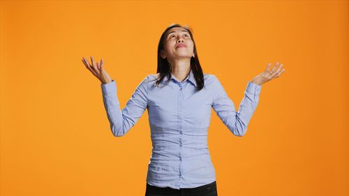 Young woman standing against yellow wall