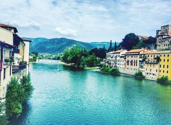 Houses by river against sky