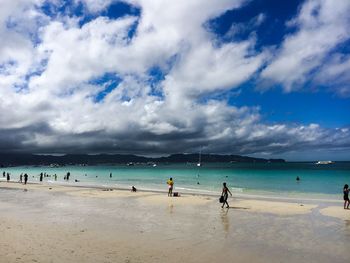 People enjoying on beach against blue sky