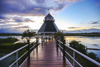 Gazebo by lake and building against sky