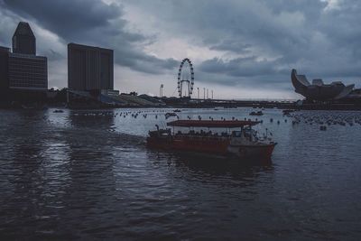 Boats in sea against cloudy sky