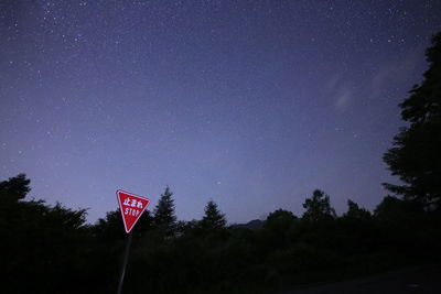 Low angle view of sign against sky at night