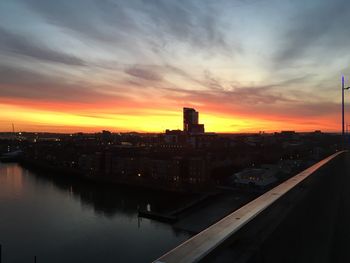 High angle view of river by buildings against sky during sunset