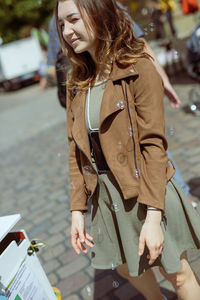 Smiling young woman standing on street in city