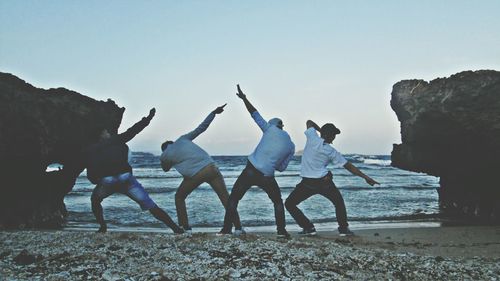 People standing on beach against clear sky