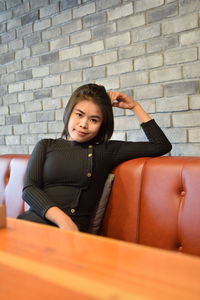 Portrait of young woman sitting on sofa in cafe