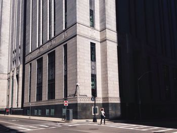 Low angle view of woman crossing road against buildings