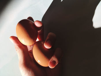 Close-up of hand holding eggs against wall