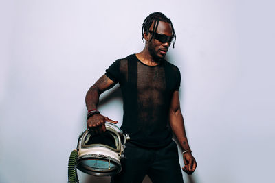 Young man wearing sunglasses standing against white background