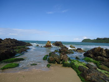 Rocks on beach against blue sky