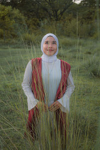 Portrait of smiling young woman standing on field