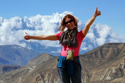 Happy girl is standing, arms outstretched, against annapurna massif. upper mustang. nepal.