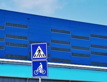 Low angle view of blue building against clear sky and road sign