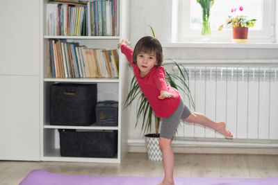 Child girl performs the exercise gymnastics at home on a mat. health and sports