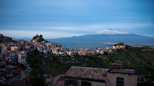 Scenic view of residential district and mount etna against sky