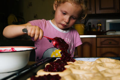 A girl prepares pies with lingonberries in the kitchen