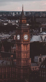 Clock tower amidst buildings in city at dusk