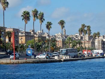 Sailboats in sea by buildings against sky