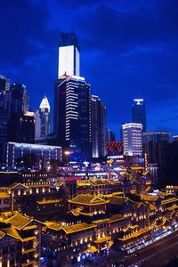 Illuminated buildings in city against sky at night