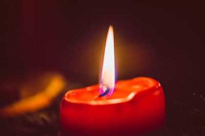 Close-up of lit candle in darkroom
