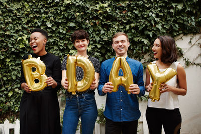 Portrait of smiling friends standing against plants