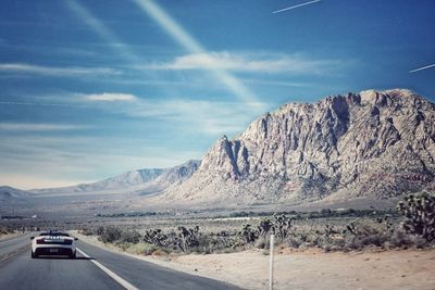 Road by mountains against sky