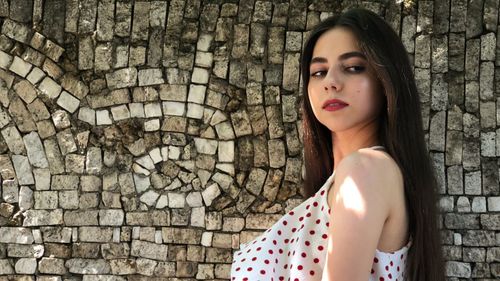 Portrait of a woman standing against brick wall