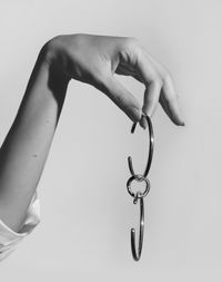 Close-up of hand holding metal against white background