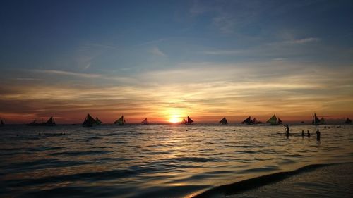 Silhouette boats sailing in sea against sky during sunset