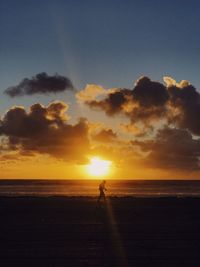 Silhouette man on beach against sky during sunset