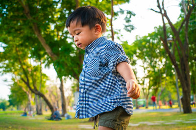 Cute boy standing against trees