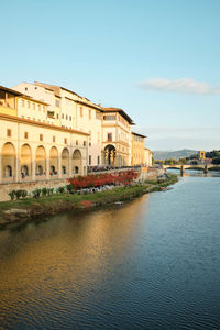 Buildings by river against clear sky