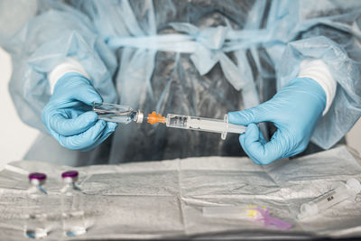 Midsection of scientist holding syringe at laboratory