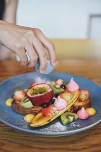 Cropped image of hand pouring syrup on food served in plate