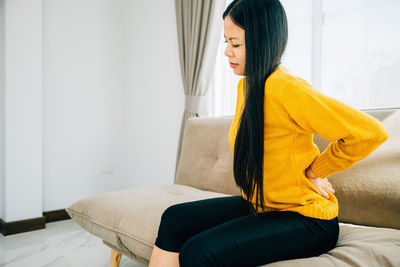 Young woman sitting on sofa at home