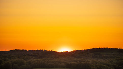 Scenic view of field against orange sky