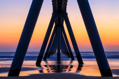 Silhouette pier on beach against sky during sunset