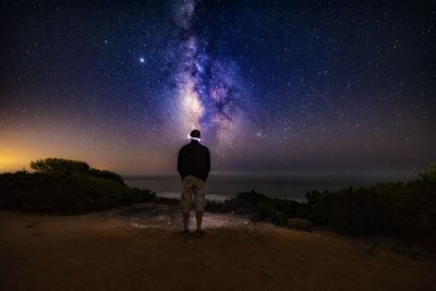 Rear view of man standing against sky at night